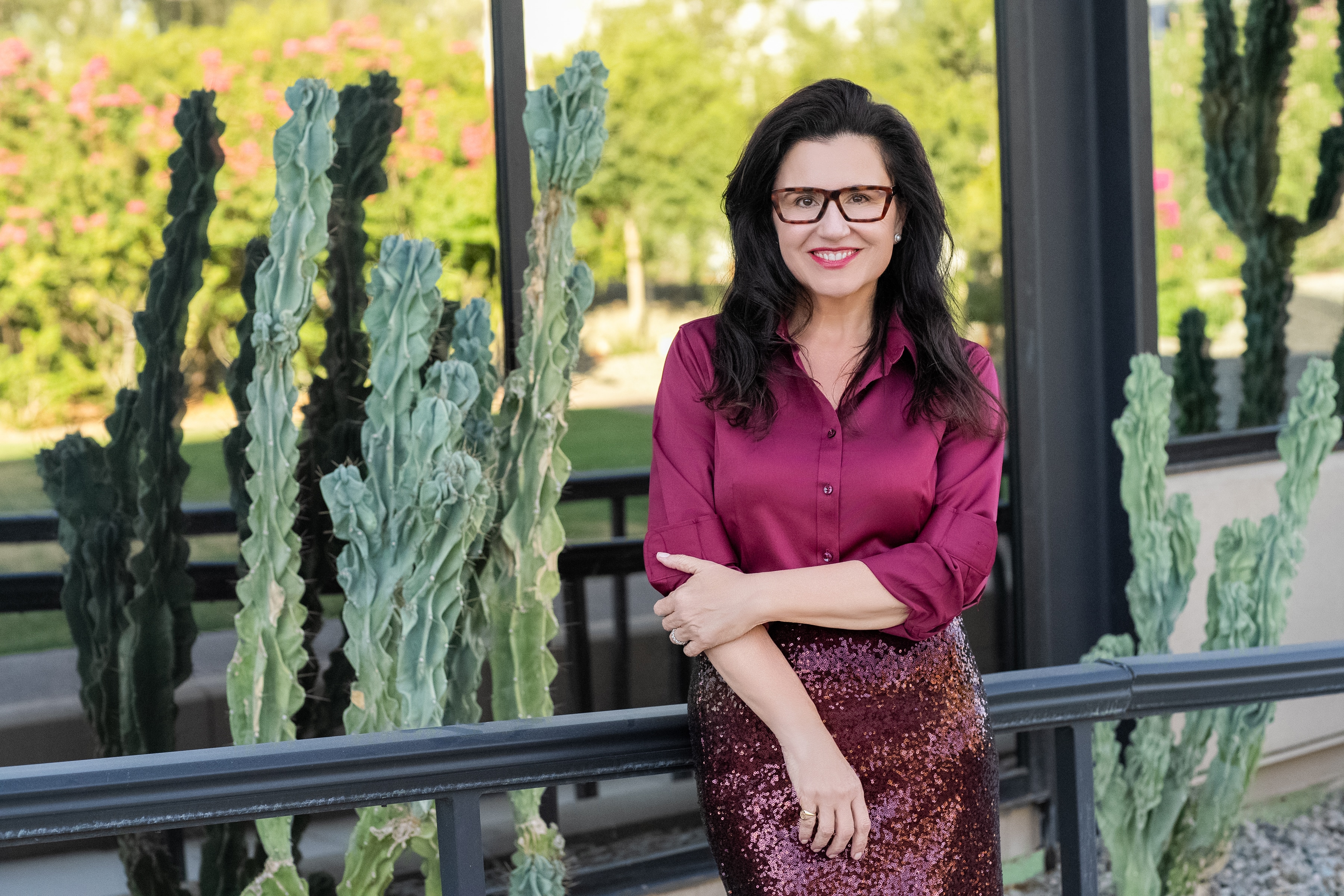 Ana Benitez standing by cactus landscaping in a burgundy shirt.