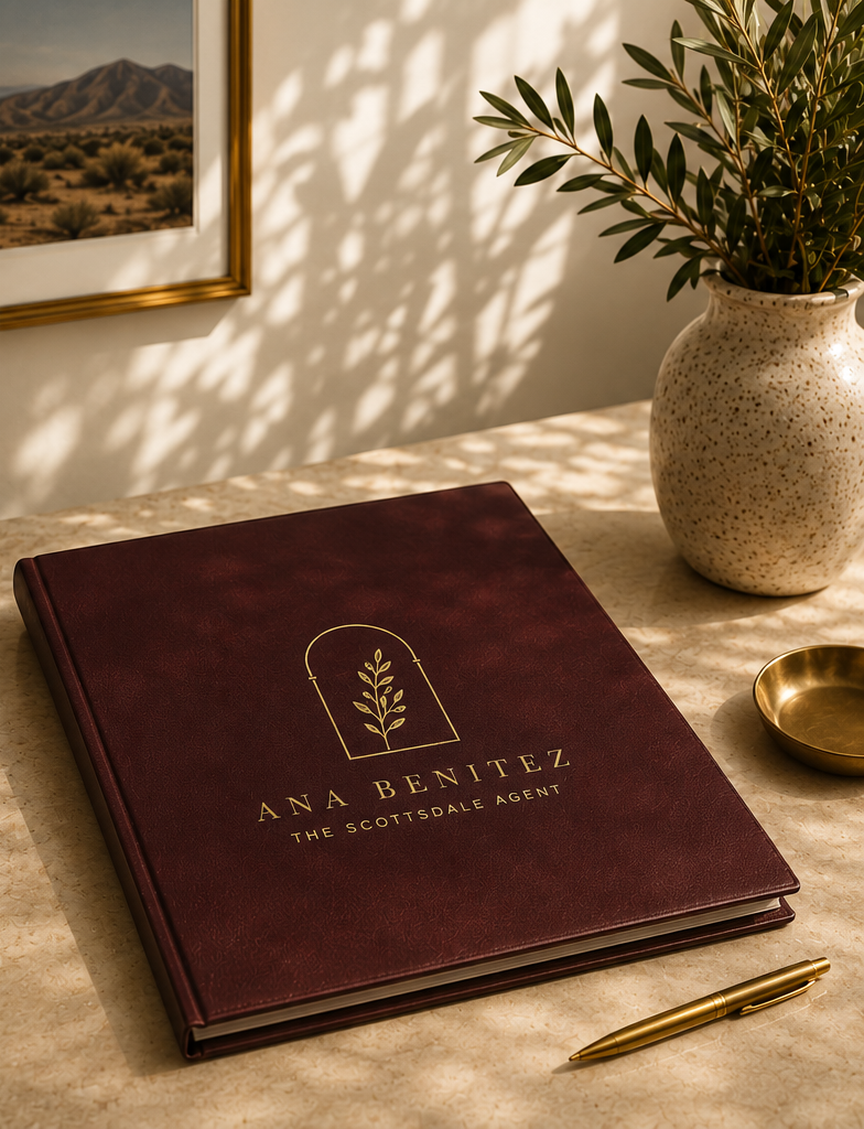 An Ana Benitez branded burgundy portfolio on a sunlit desk with olive branches.
